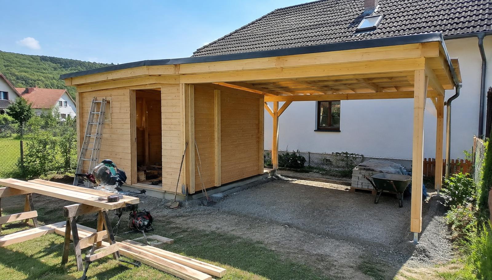Drobná dřevěná zahradní stavba na pozemku rodinného domu s plány a metrem na stole v popředí